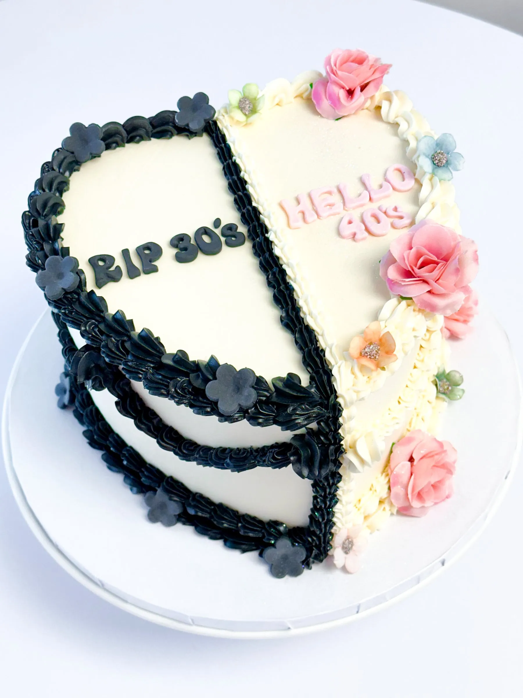 Heart-shaped cake split in half, one side reading RIP 30's and the other Hello 40s